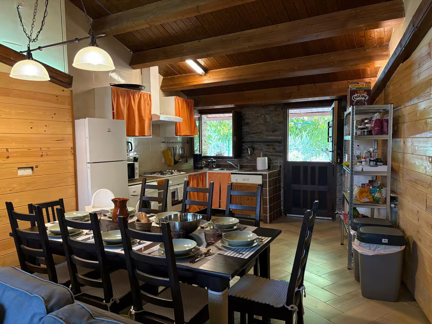 Esta acogedora zona de día combina el encanto rústico de las paredes de madera y piedra con una cocina totalmente equipada y un amplio comedor con capacidad para grupos grandes. Ideal para disfrutar de comidas caseras y veladas inolvidables, con acceso directo a un jardín privado y la montaña. Un espacio funcional y cálido para el día a día.